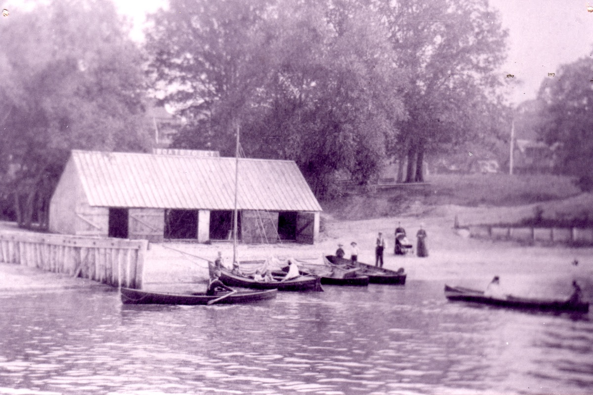 Photograph of the lakefront boat and bath house at Ryerson Park, with rowboats and visitors at the water's edge.